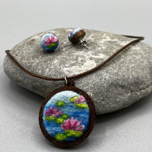 Necklace and earrings containing lotus flowers photographed on top of a rock